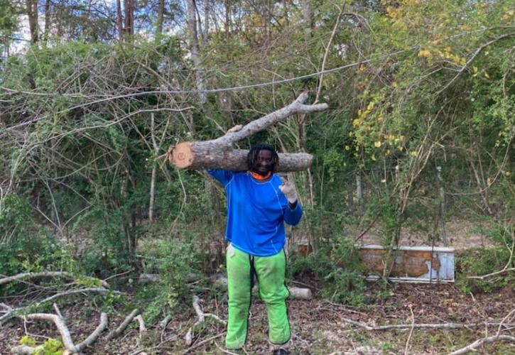 A-DRT team member Jamarri Shah hauls away a tree limb after using a chainsaw to cut the downed tree into manageable pieces.