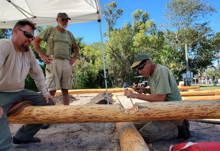 three men chipping a pine log