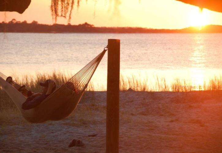 a hammock with two people in it hangs on a beach