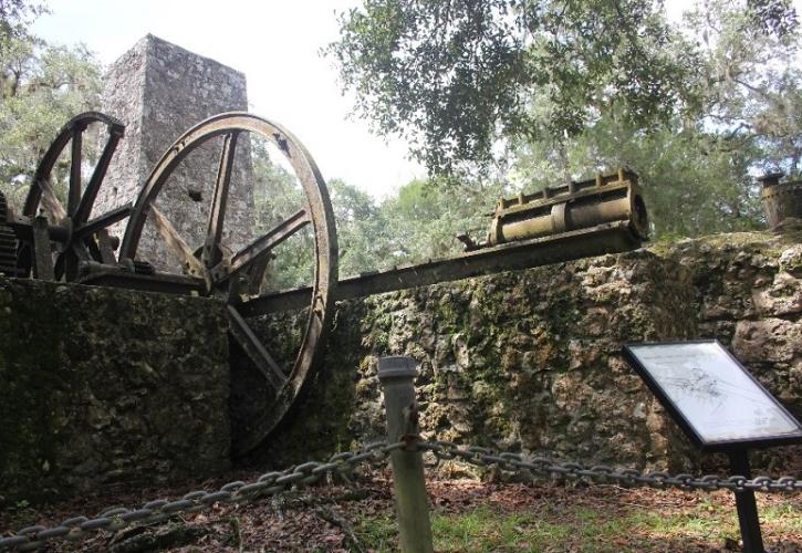 a stone building with metal wheels and other parts and a sign