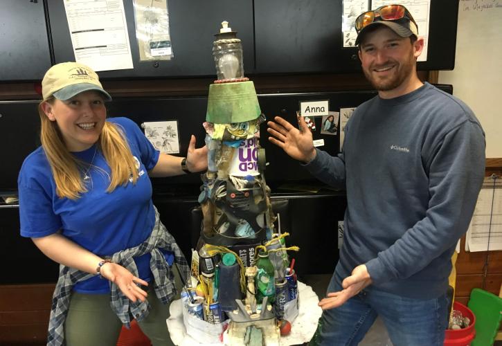 Anna and a coworker show the litter collected during a river clean up event.