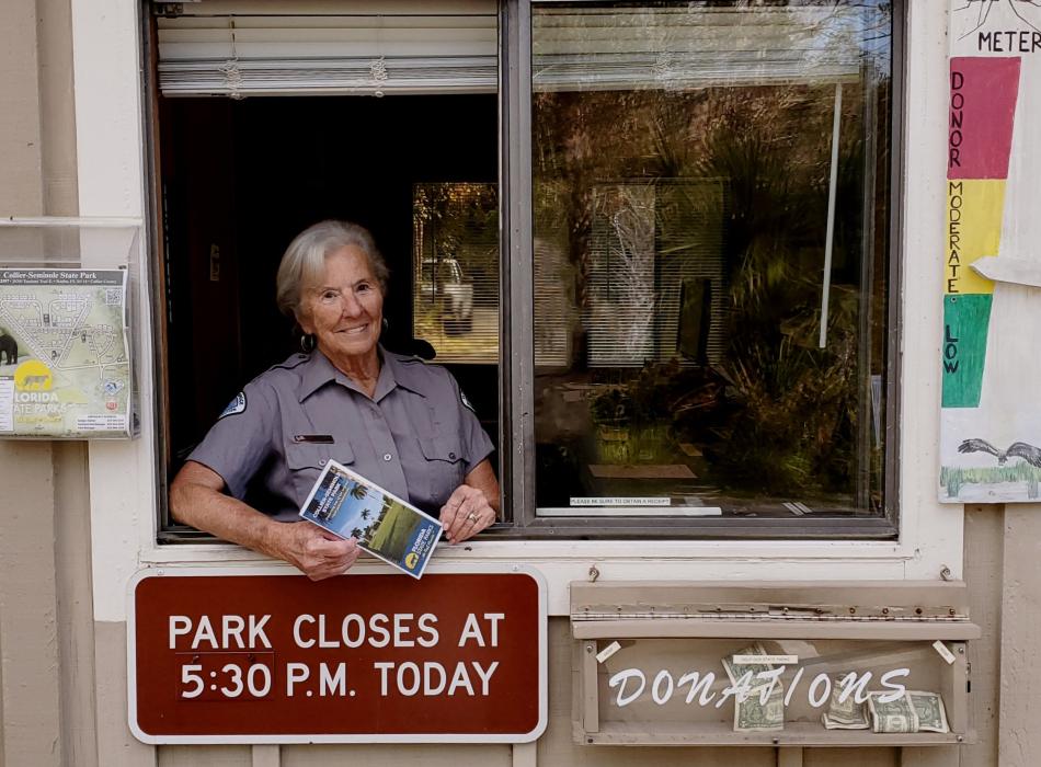woman standing in a window smiling holding a brochure