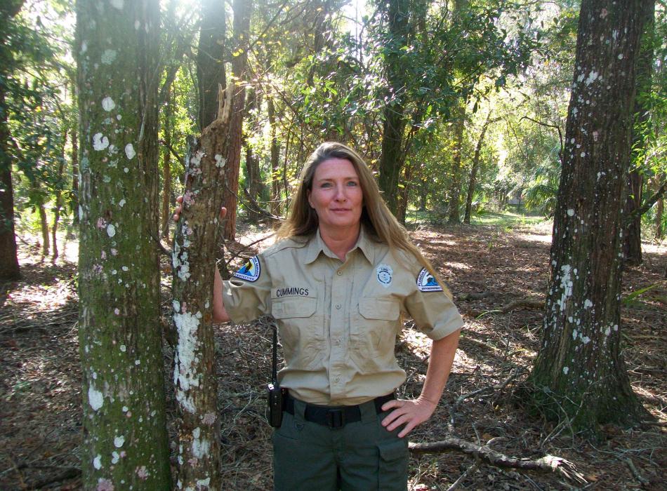 Park Ranger Jane Cummings in the forest smiling at the camera