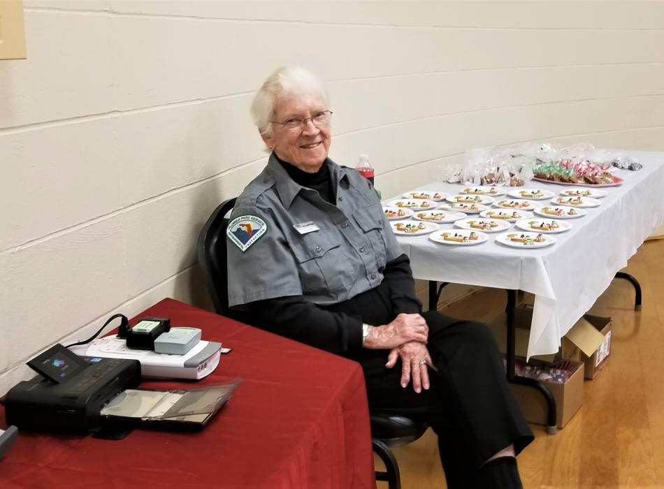 A woman in a grey shirt sits at a table. 