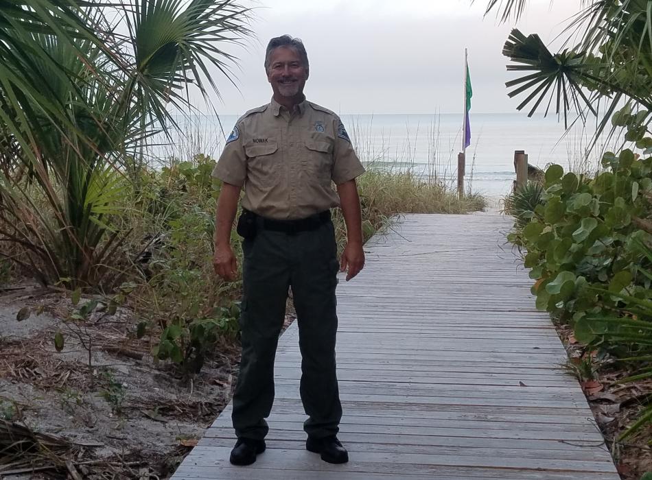 Terry Nowak standing on a boardwalk with the beach behind him