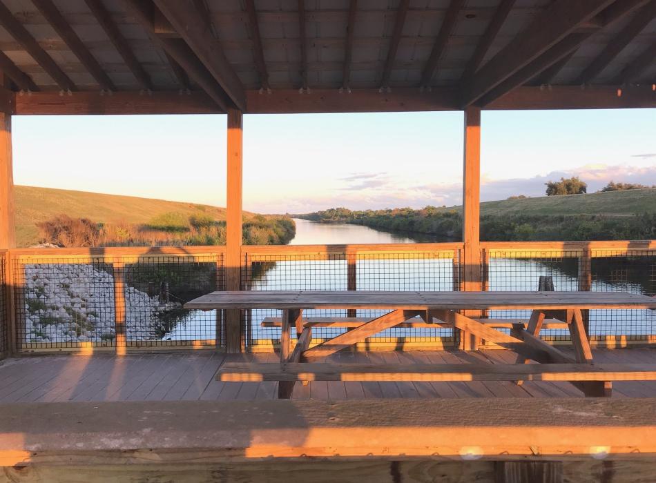Wooden outlook that has wooden picnic tables during sunset