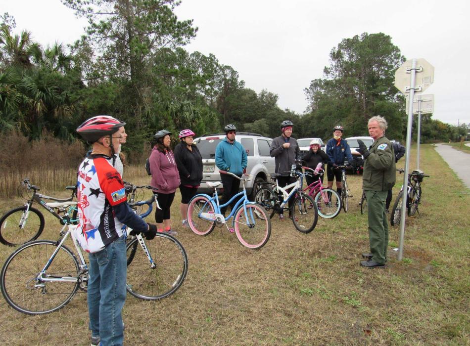 A man stands next to a group of people with bicycles. 