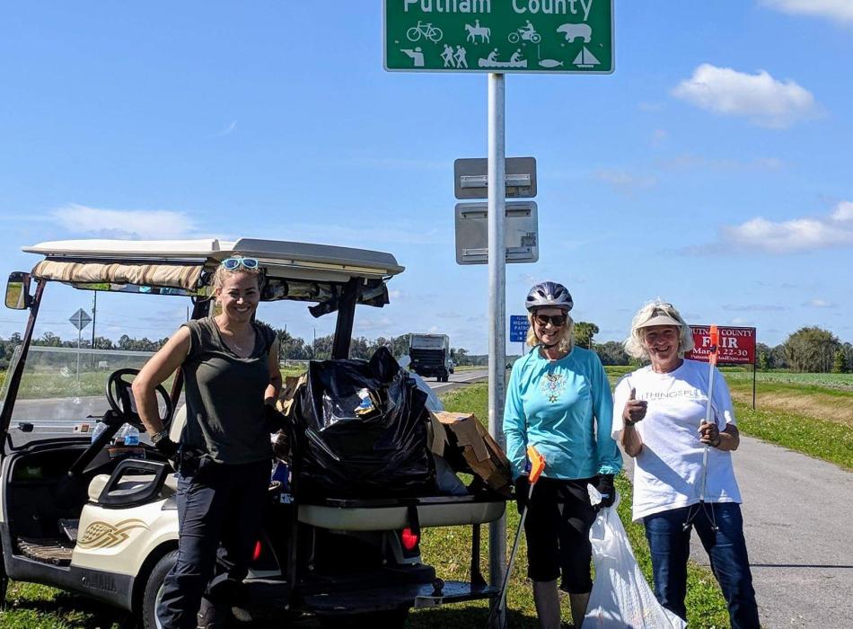 Three women next to a golf cart on a trail. 
