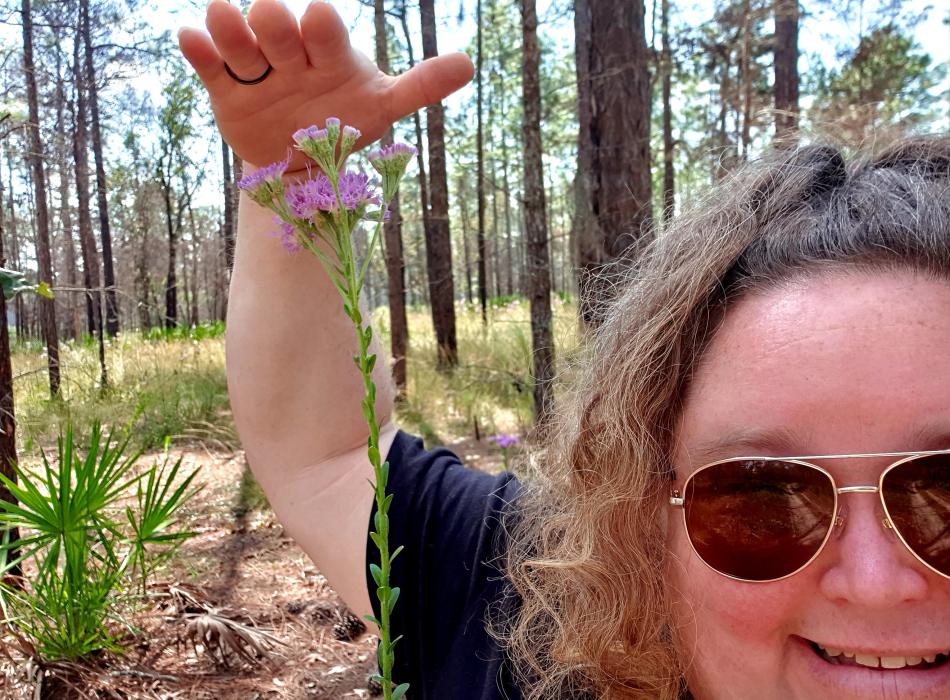 Nicky measures the height of a plant against her own height.