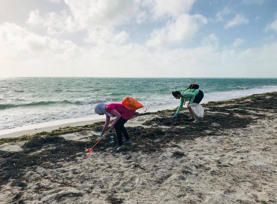 Two volunteers picking litter off the beach