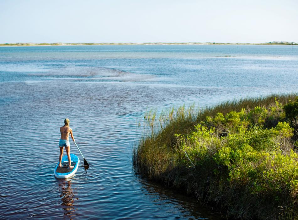 Paddler traversing coastal waters.