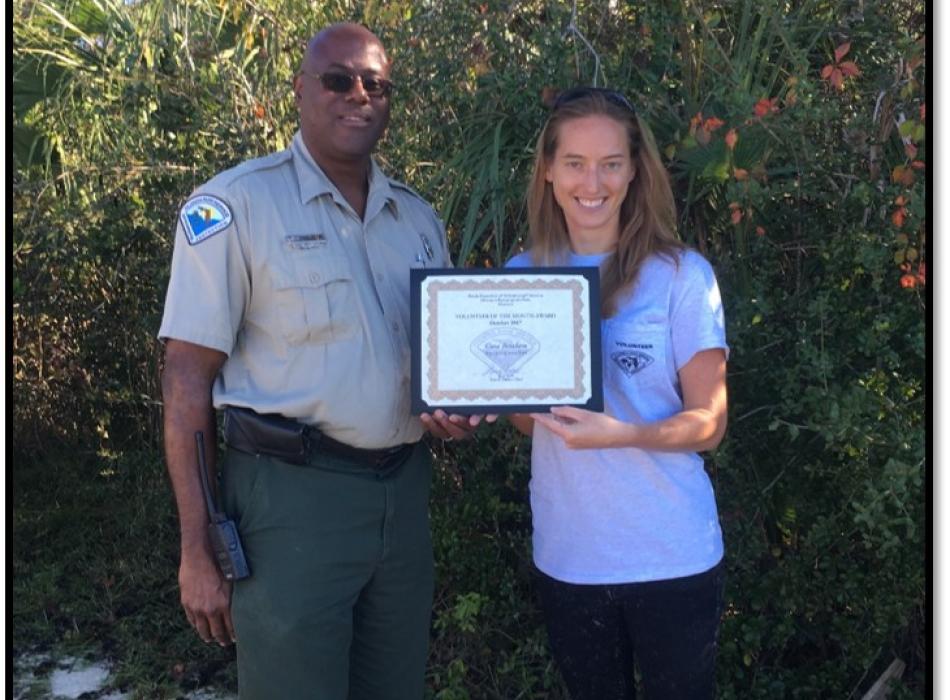Cora, standing with an award certificate next to a ranger.