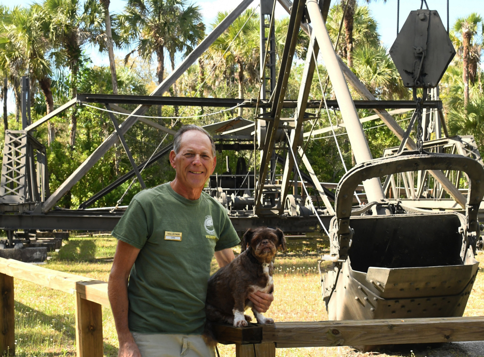 person standing with a dog at a dredge