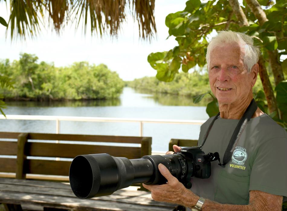 person holding camera standing near a river