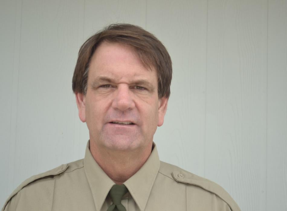 Dennis, in his ranger uniform, smiling at the camera.