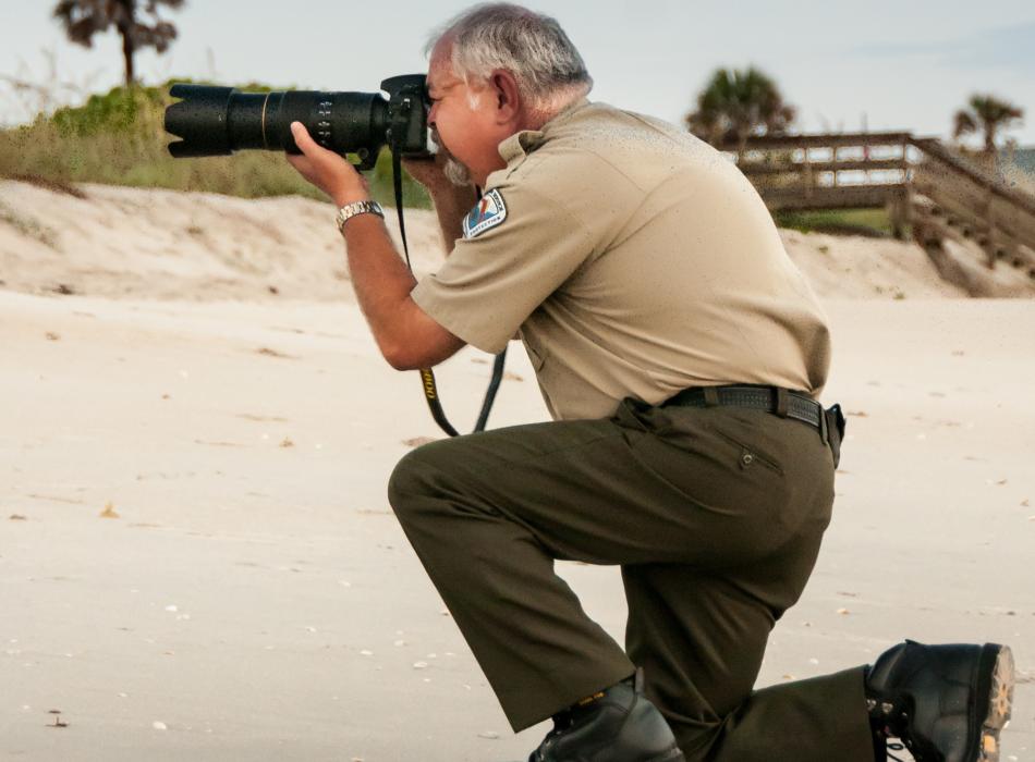 Ed, in his ranger uniform on the beach, taking photos.