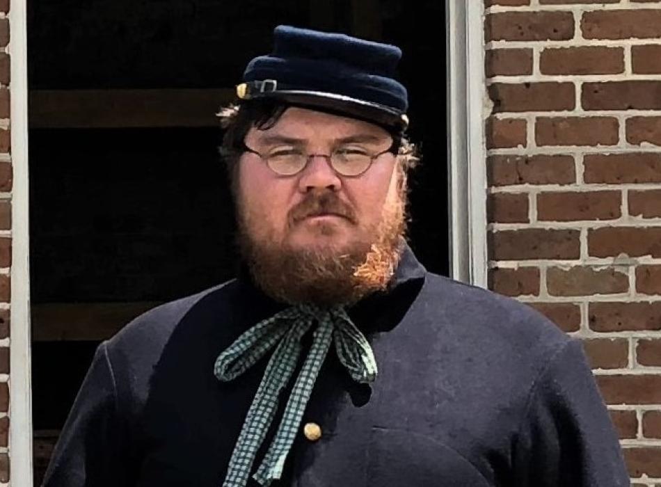 Andy, dressed as a Civil War Soldier, in front of a brick building.