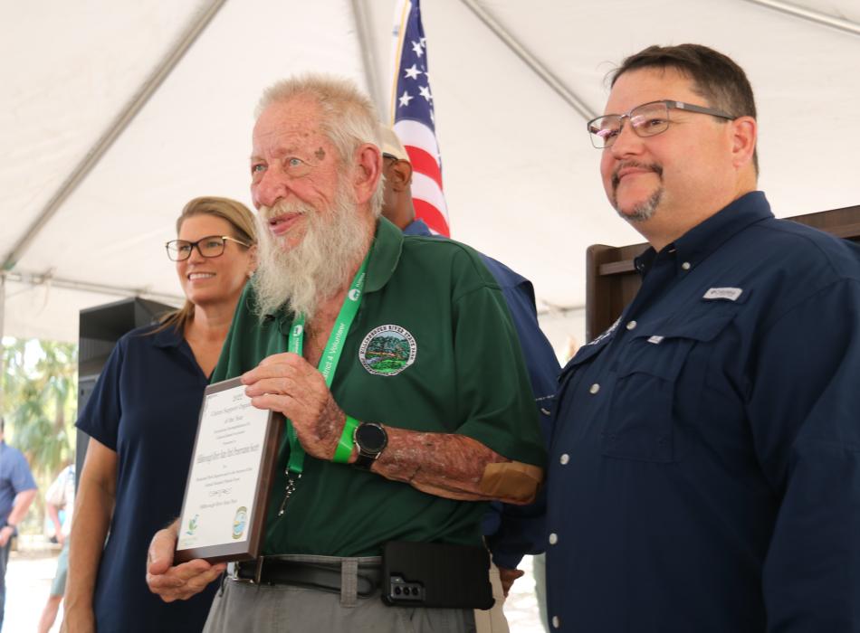 A representative accepts the award from Emily Lewis and Brian Fugate.