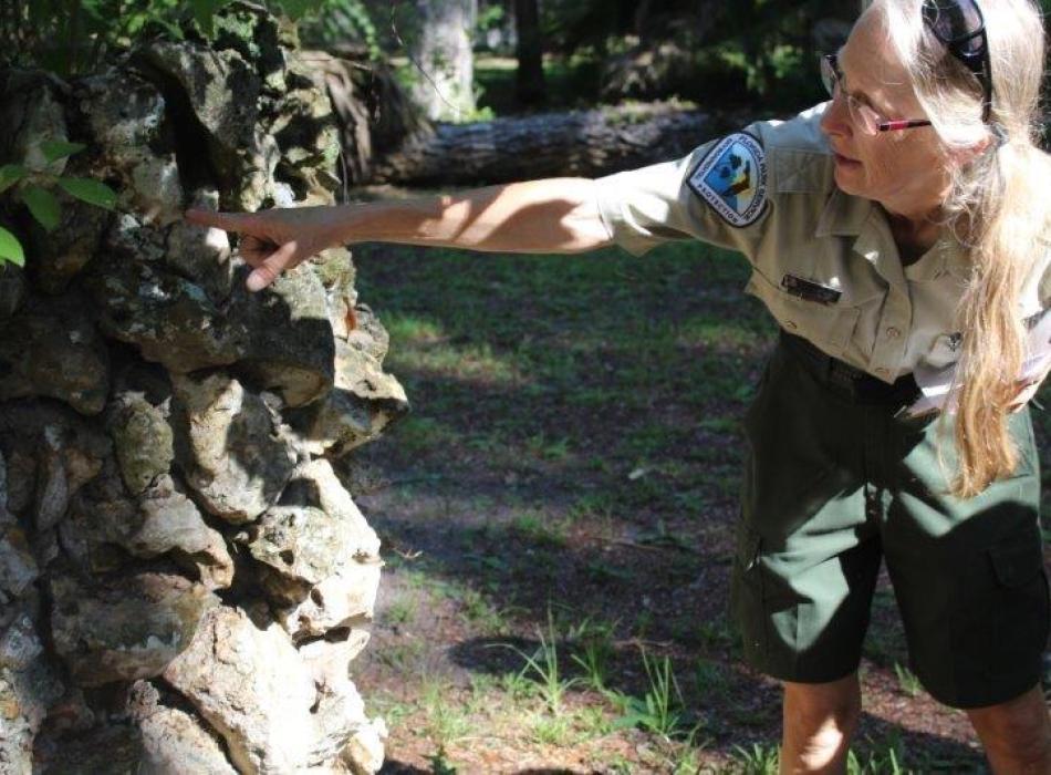 Kristin, pointing at a rock, wearing her ranger uniform.