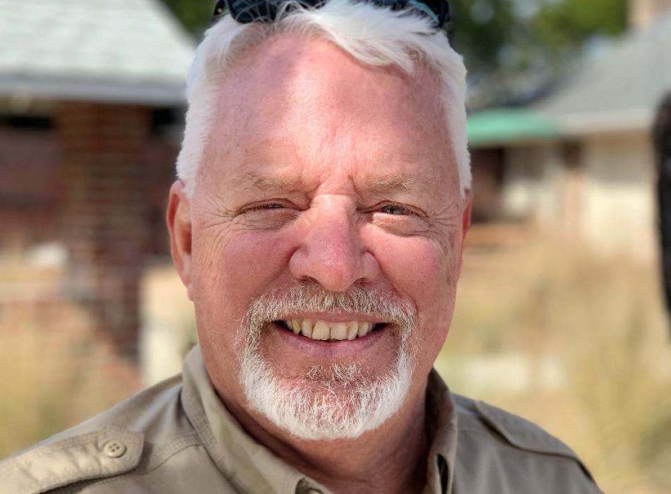 a white haired man smiles at the camera