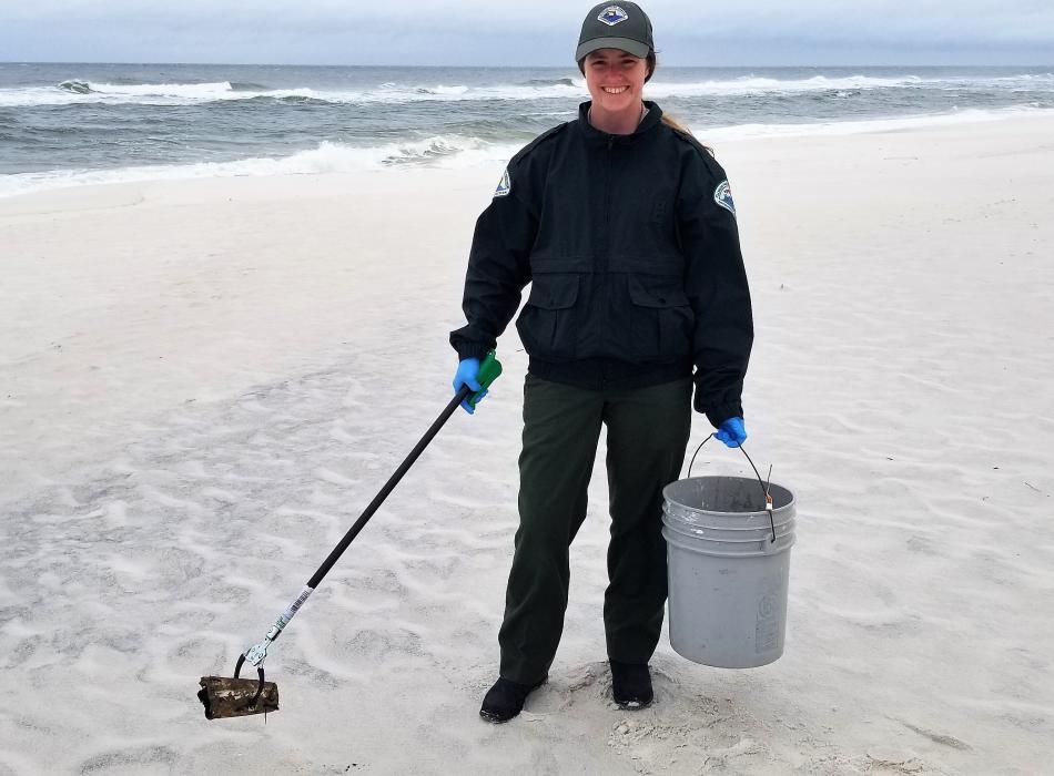 Jessica Ryan picking up trash along the beach.