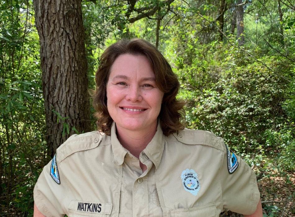 a woman in uniform leans on a railing and smiles