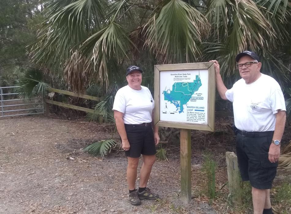 Volunteer Nick and Darlene Divirgilio pose next to trail sign at Econfina River State Park. 