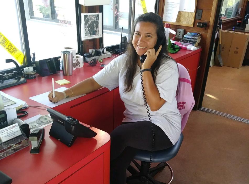 Deysi, sitting at a desk answering the phone.