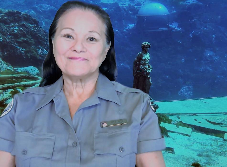 Rita King, smiling at the camera, standing in front of the underwater observatory.