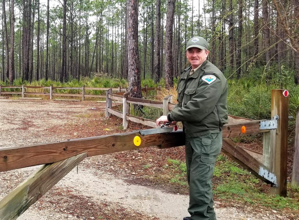 Scott Hoxie standing by a gate in his ranger uniform.
