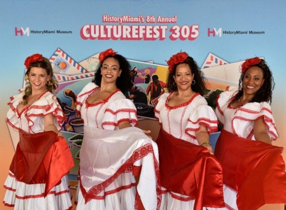 Four people in adorned red and white satin dresses performing a synchronized dance move.
