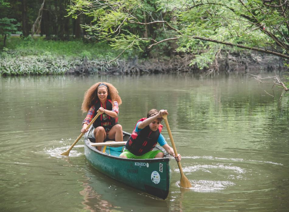 Youth paddle through a waterway