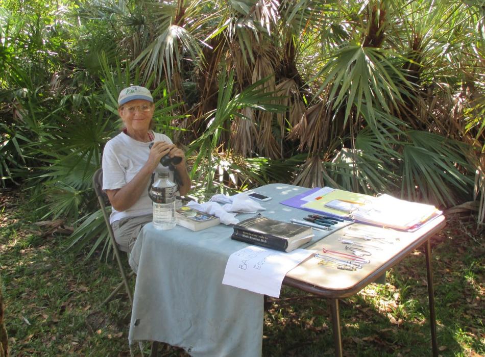 Volunteer Meret Wilson with her bird banding station and binoculars in hand