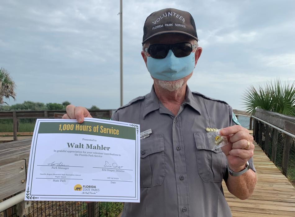 Volunteer Walt Mahler stands near the beach walkover with his recently earned 1,000 hours certificate and pin. 