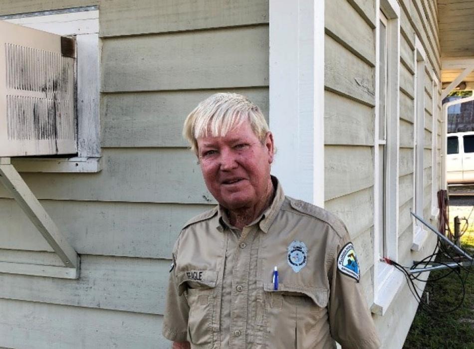 a man in uniform with white hair stands next to a building smiling