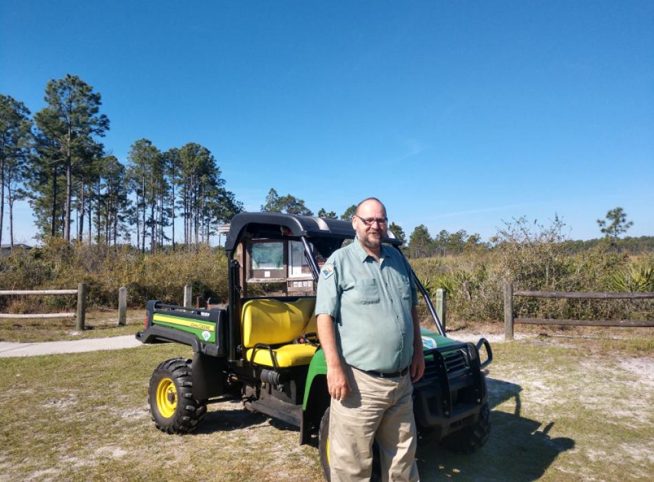 a man in uniform stands next to a golf cart