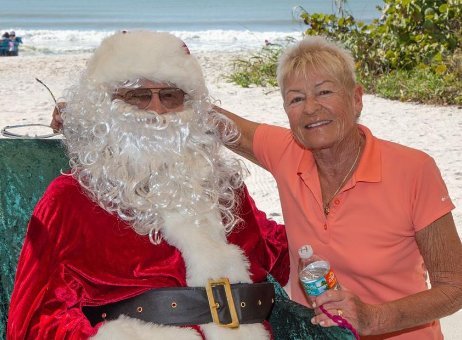Ingrid Twiefel smiling at the camera, sitting next to her husband Richie dressed up as Santa for an event.