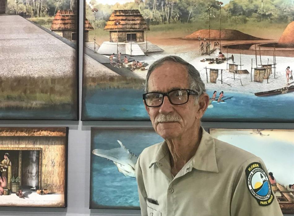 A man in uniform stands in front of a museum background