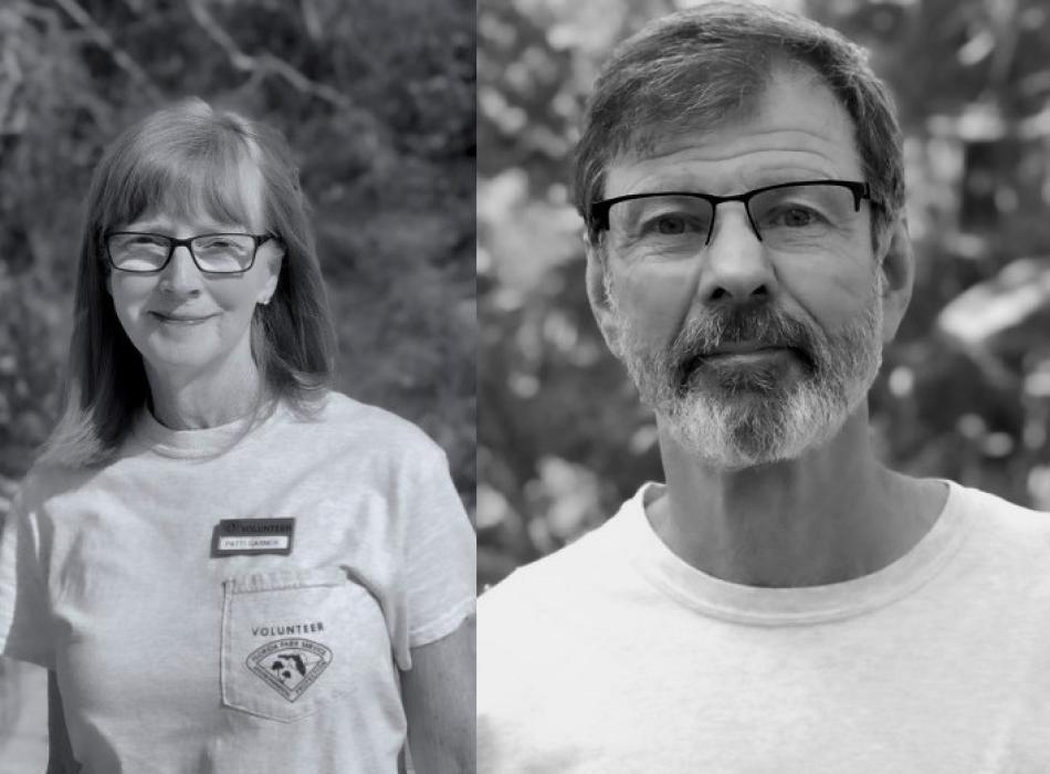 a woman and man in glasses and volunteer uniforms smile