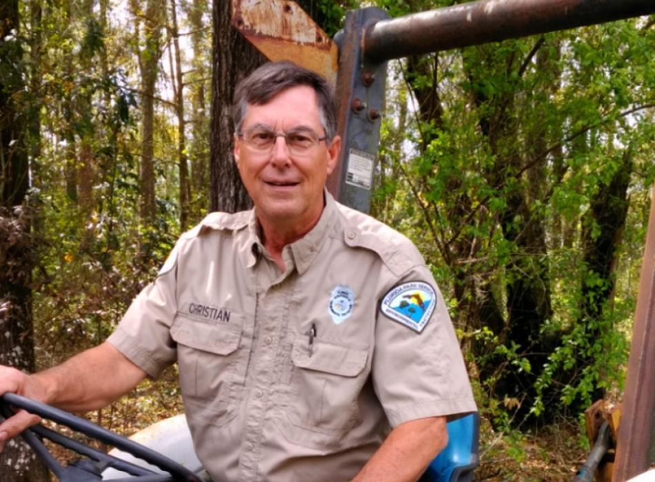 a man in park service uniform sits on a tractor